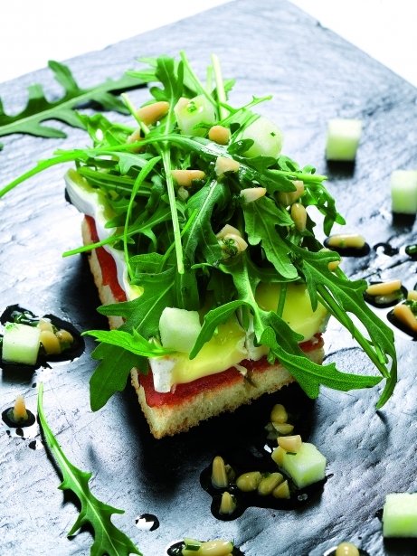 Ensalada de queso y rúcula sobre una tostada de membrillo y vinagreta