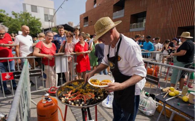 Un participant en el concurs de paelles reparteix plats als assistents
